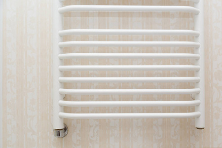 墙上挂白色毛巾轨散热器在现代浴室的钙华瓷砖