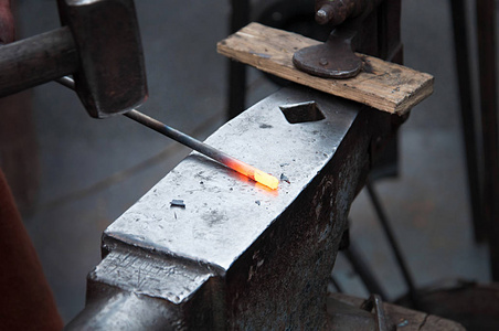 手工烟花手工锻造熔融金属在铁匠铺里铁砧上的铁匠照片