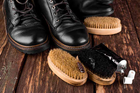 黑色靴子的木制背景抛光设备, 刷子和波兰奶油