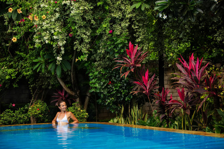 Caucasican 妇女休息在蓝色水池在热带