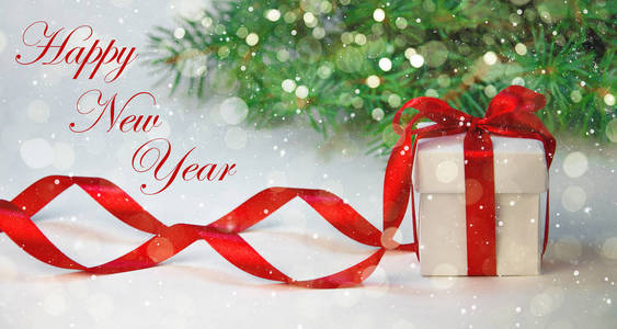 圣诞节礼物在白色盒与红色丝带在光背景与冷杉树。新年假期作文