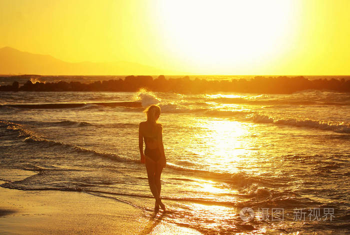 剪影的年轻漂亮的女孩在关门的海边日落