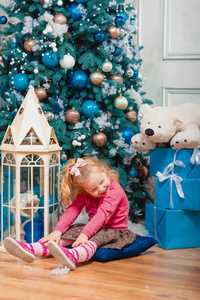 金发碧眼的小女孩坐着, 微笑着几乎装饰圣诞树