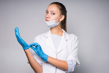 智能严重的女医生在白色的医疗睡衣穿上蓝色硅胶手套手