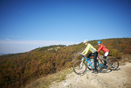 两个女骑自行车的人在山上骑自行车时欣赏美丽的风景。