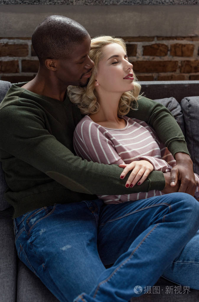性感的非裔美国人男人拥抱女朋友一起躺在沙发上