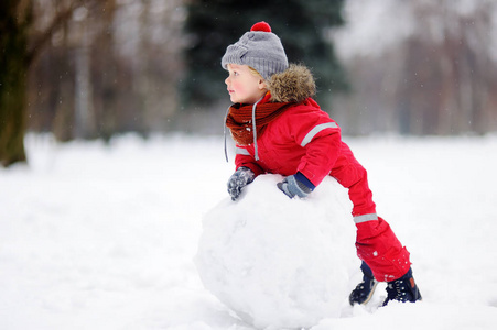 小男孩在玩堆雪人的红色冬衣