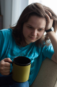 房间里一个迷人的女孩从一个大杯子里喝茶。