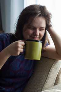 房间里一个迷人的女孩从一个大杯子里喝茶。