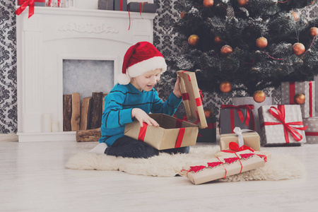可爱的男孩，在圣诞老人的帽子展开圣诞礼物