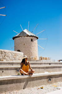 古老的风车附近的女孩。在欧洲，度假，旅行的暑假。西班牙，希腊，土耳其