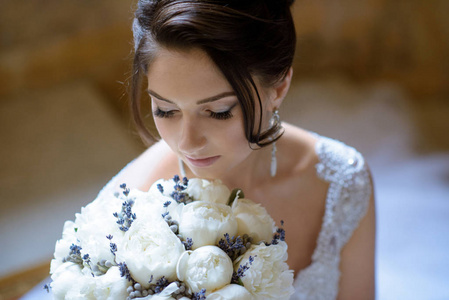 美丽的新娘在婚纱与花束和蕾丝面纱在室内