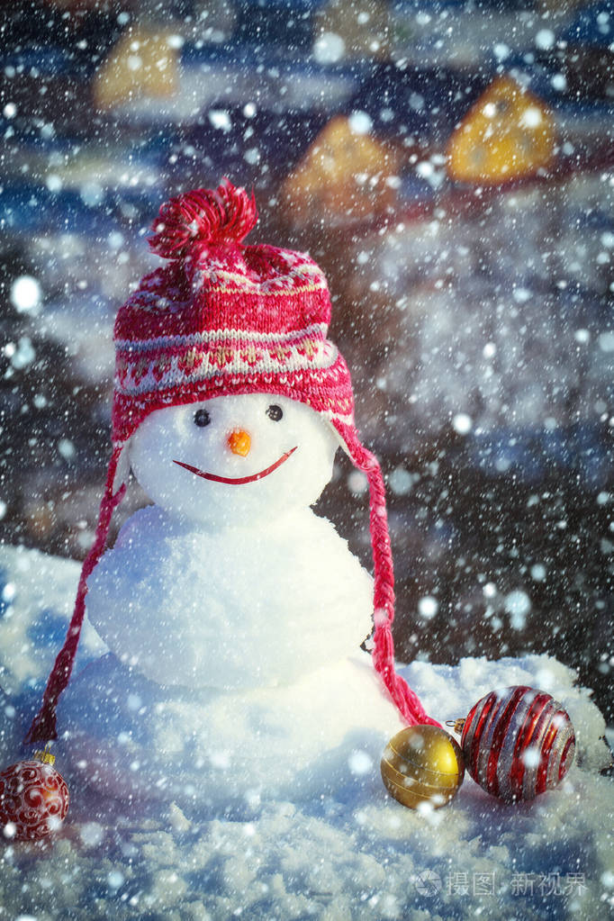 雪人在农村背景上顶红色的帽子