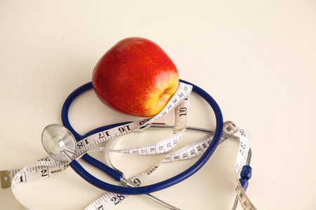 苹果躺在一张桌子上，用听诊器和测量卷尺