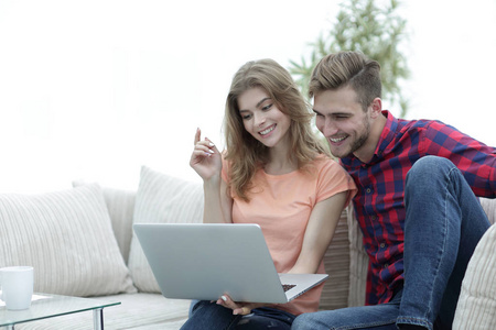 年轻人与他的女朋友看电视节目在手提电脑坐在客厅里