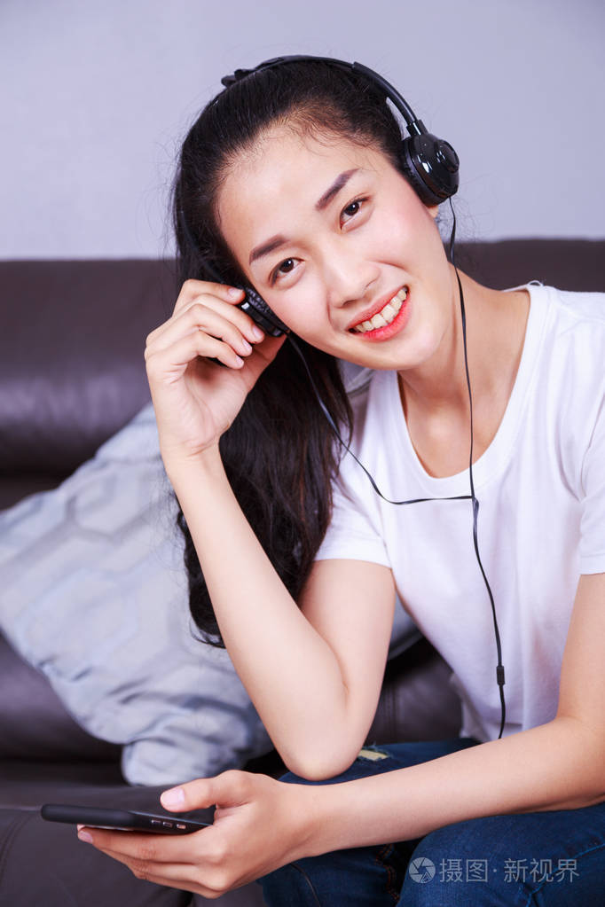 手机在沙发上听音乐的少妇
