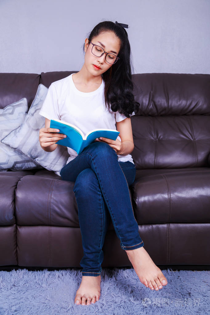 读一本书在家里的沙发上的女人