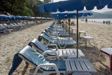 太阳床上有雨伞，海滩上有白沙，在泰国。