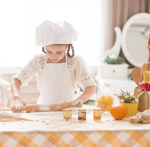 逗人喜爱的小女孩在厨师的形式烹调可口食物在厨房