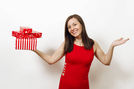 美丽的白种人年轻快乐的女人穿着红色的礼服和圣诞帽在白色背景下手捧礼品盒。礼物被隔绝的圣诞老人女孩。新年假期2018概念
