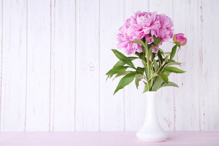 粉红色木桌上花瓶中的牡丹花束