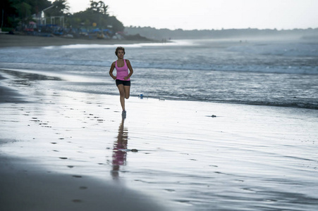 年轻有吸引力和适合亚洲体育赛跑者妇女奔跑在海滩海边微笑愉快在健身