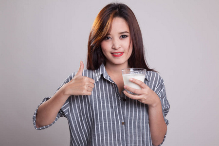 健康的亚洲女人，喝一杯牛奶的拇指