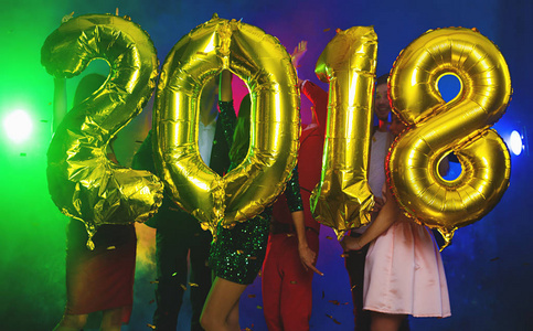 金色气球的组成，以数字的形式出现在一群年轻人的背景上。 新年，新年聚会或迪斯科。