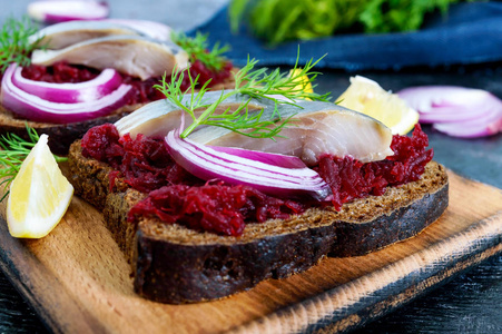 饮食三明治与甜菜片咸鲱鱼和红洋葱在黑背景黑麦面包。