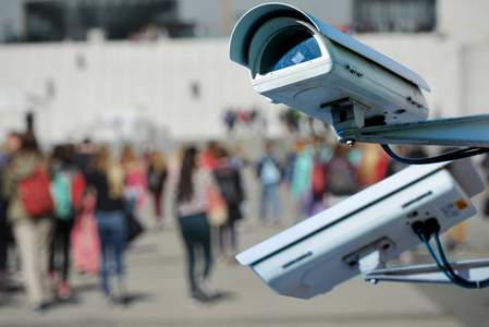 安全闭路电视摄像头或监控系统在街上与游客模糊背景