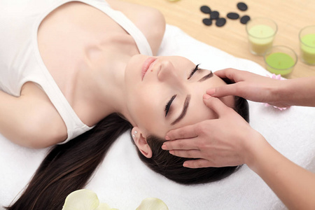 脸部穴位脸部按摩.得到温泉治疗一个年轻女人的特写照片