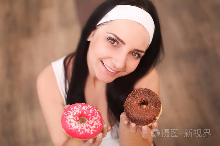 美女时装模特女孩吃甜食和五颜六色的甜甜圈有趣的快乐风格的女人与