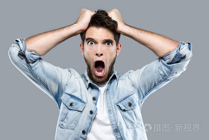 愤怒的年轻人在灰色背景下尖叫