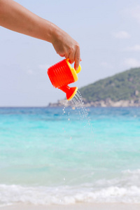 女性的手从孩子的塑料浇灌罐头倾吐水。安达曼海, 斯米兰群岛