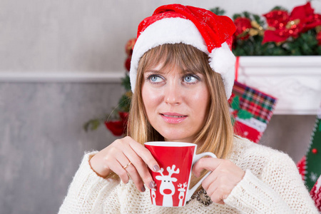 圣诞节或新年庆祝。在圣诞树背景下喝杯热饮料的女人手里的杯子, 快乐的假日概念
