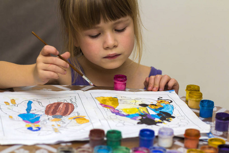 逗人喜爱的小女孩绘画用刷子和五颜六色的油漆