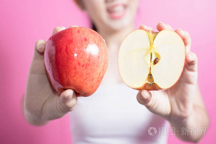 亚洲妇女与苹果概念。她笑着抱着苹果。美丽的脸庞和自然的妆容。在粉红色背景上隔离