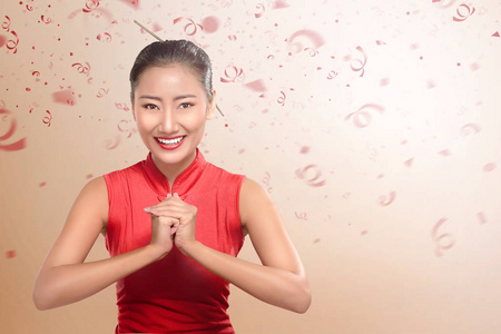 中国美丽的女人穿着传统的衣服，用手势。 新年快乐