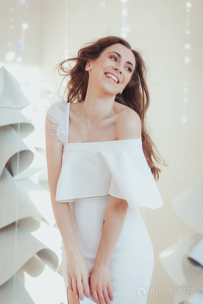 美丽的年轻模特在摄影棚里微笑和摆姿势, 时尚面料圣诞树上的背景