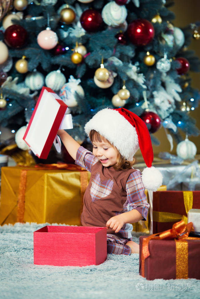 愉快的小女孩打开一个箱子与礼物为圣诞节
