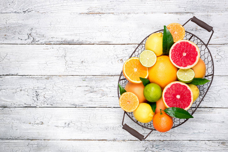 柑橘类水果背景。果在篮子桔子, 葡萄柚, 柠檬, 石灰, 桔子。新鲜的柑橘类水果和树叶。顶部视图