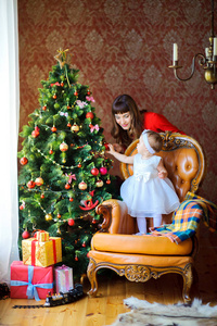 快乐的小女孩和她的母亲一起装饰节日的圣诞树