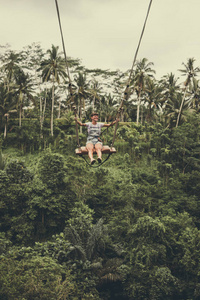 印度尼西亚热带巴厘岛的丛林雨林中, 年轻的旅游妇女在悬崖上摇摆
