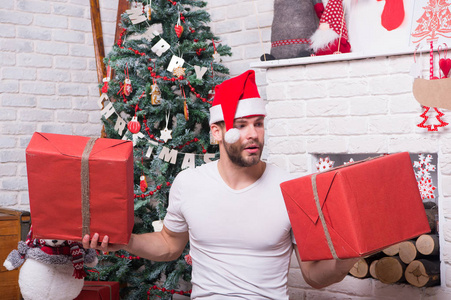 男子气概在圣诞老人的帽子举行包裹在壁炉的礼物