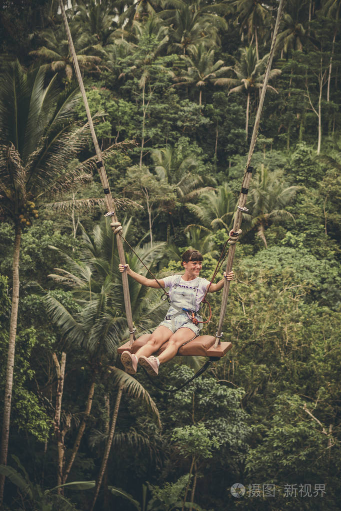 印度尼西亚热带巴厘岛的丛林雨林中, 年轻的旅游妇女在悬崖上摇摆
