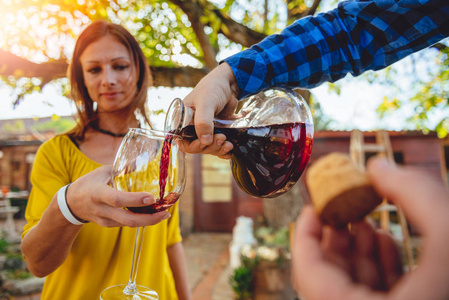 男人在后院的露台上把红酒倒入女人的酒杯