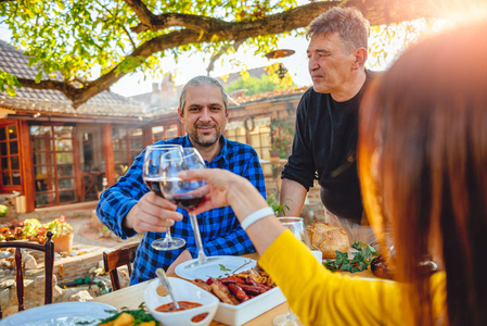 男人和女人在后院露台的家庭午餐上品尝红酒
