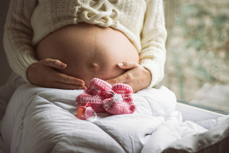 怀孕的妇女在她的腹部举行她的手, 在她旁边是别针