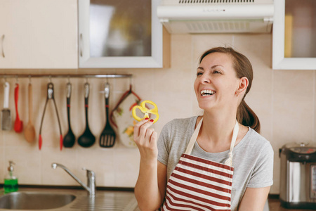 一个穿着围裙的年轻快乐迷人的女人在厨房里放着黄胡椒。节食概念。健康的生活方式。在家做饭。准备食物