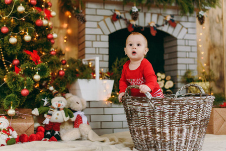 快乐可爱的小男孩的肖像, 谁坐在篮子在家里的装饰房间。圣诞节好心情。新年。生活方式家庭和团结概念